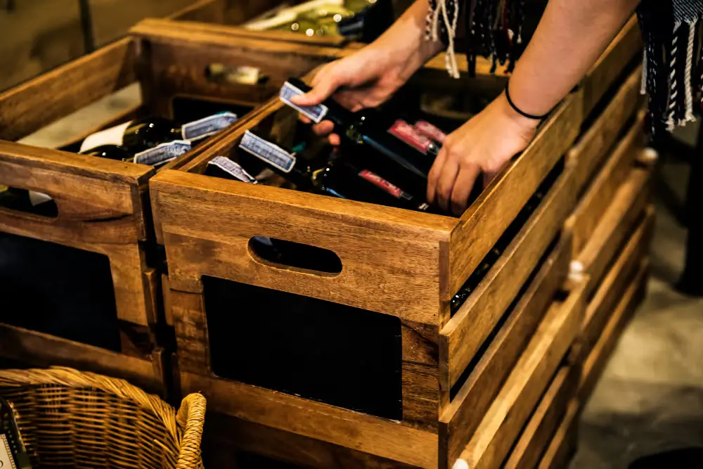 Hands lifting bottles from a wooden wine crate