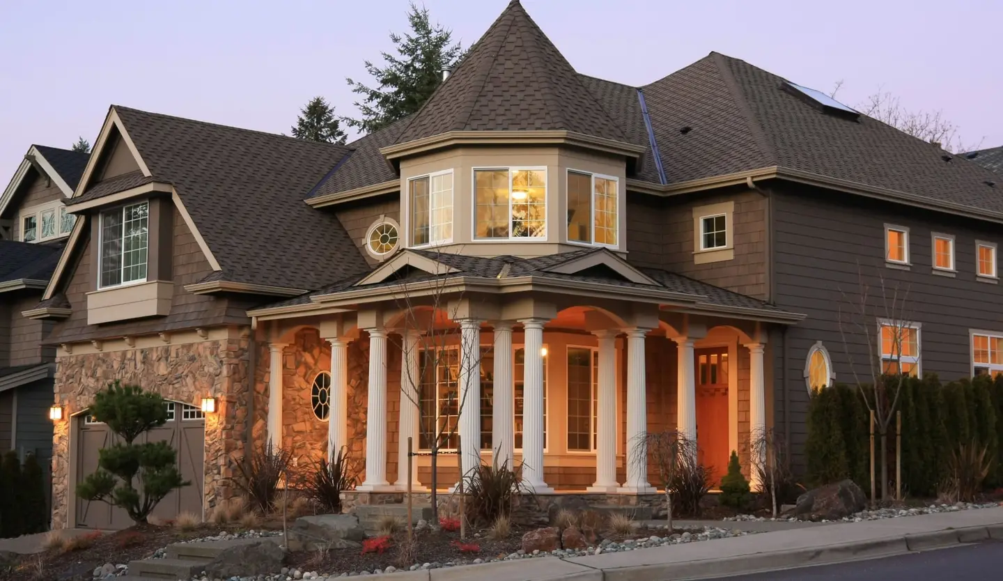 Large house with a lit veranda at dusk