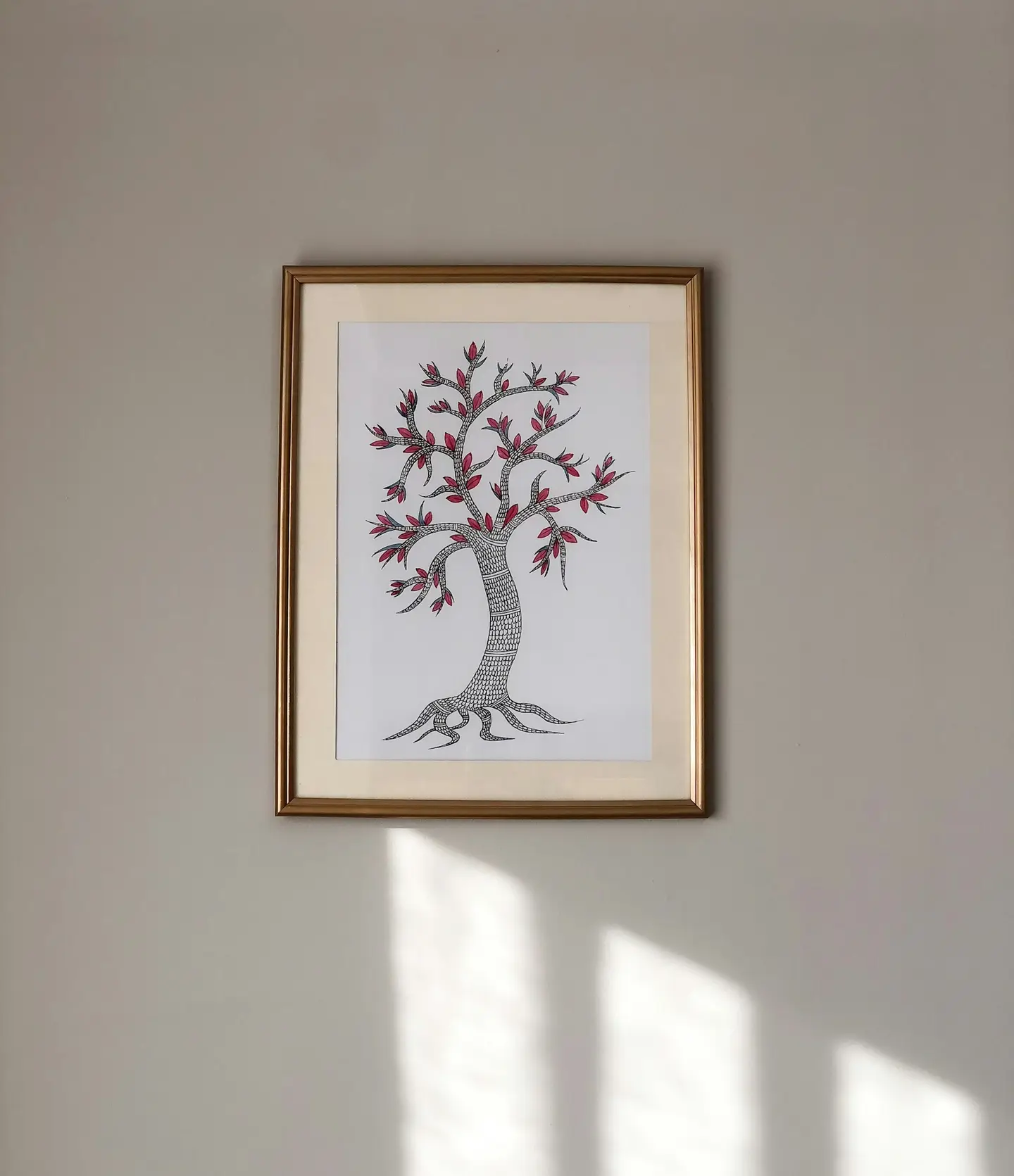 Framed artwork of a tree hanging on a sunlit wall